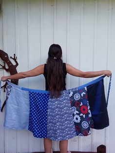 a woman standing in front of a white wall holding up several pieces of cloth