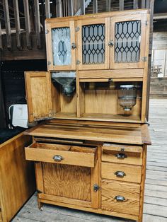 an old wooden hutch with glass doors on the front and side drawers in it