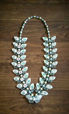 a necklace made out of dollar bills and pearls on a wooden table with the words money written