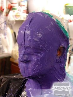 a purple mask is being made in the shape of a man's head with green hair