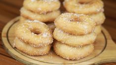 several sugared donuts stacked on top of each other in a wooden platter