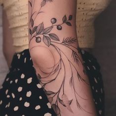 a woman's arm with flowers and leaves tattoo on her left side, while she wears polka dots