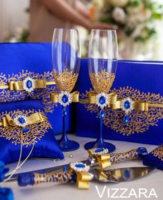 two wine glasses with blue and gold decorations sit on a table next to other items