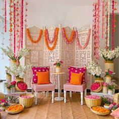 a decorated stage with pink chairs and flowers on the floor, along with other decorations