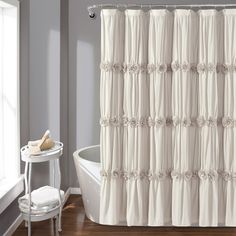 a white shower curtain in a bathroom next to a tub