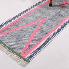 a colorful rug with fringes on top of it next to a wooden table and chair