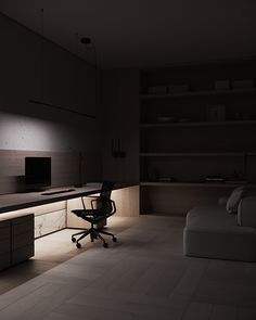 a dimly lit room with a couch, desk and television on the wall next to it