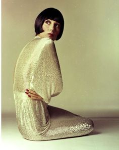 a woman sitting on the ground with her legs crossed in front of her body, wearing a gold dress