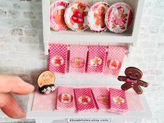 a person is pointing at some pink and white items on a display shelf with gingerbreads