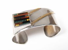 "Vintage Modernist Gemstone Inlay Square Sterling Silver 1\" Wide Cuff Bracelet Amazing modernist Sterling Silver Cuff Bracelet. Stunning design and multi inlay gemstone square! Amber, Carnelian, Malachite, Black Onyx...There are diagonal lines of separately applied gold. An extremely unique design you do not see every day. Measures 1\" wide. Beautiful piece! Inner circumference is approx 6-1/2\". Marked \"Sterling\" on the inside. We do not see a makers mark. In very good condition. May require Modernist Multicolor Jewelry For Gifts, Modernist Multicolor Jewelry As A Gift, Multicolor Modernist Jewelry As A Gift, Multicolor Modernist Jewelry For Gifts, Modern Multicolor Rectangular Jewelry, Modern Multicolor Polished Jewelry, Contemporary Rectangular Jewelry With Polished Finish, Modern Adjustable Rectangular Jewelry, Modern Rectangular Bracelet With Polished Finish