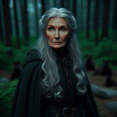 an older woman with long grey hair in the middle of a forest wearing a cloak