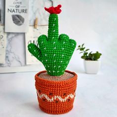 a crocheted cactus sitting on top of a pot with a red flower in it