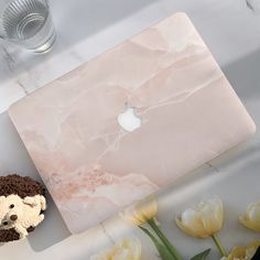 an apple laptop computer sitting on top of a white counter next to yellow tulips