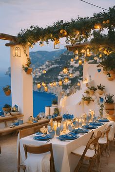 an outdoor dining area overlooking the ocean with lit candles and lanterns hanging from the ceiling