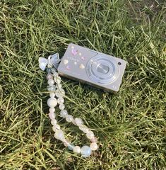 a camera is laying on the grass with beads