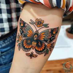 a woman's leg with a butterfly tattoo on the side of her thigh and an orange flower in the middle