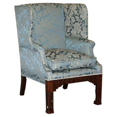 an upholstered chair with blue and white floral fabric on the armrests