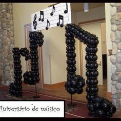 black balloons are arranged in the shape of letters and music notes on poles, along with musical notes