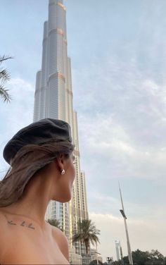 a woman standing in front of the burj building with her hair blowing in the wind