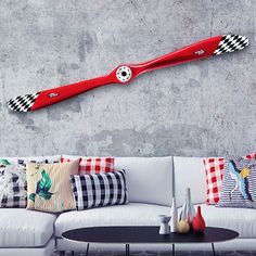 a white couch sitting next to a wall with red and black decor on top of it