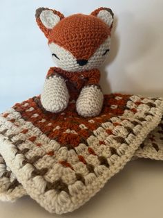 a crocheted fox sitting on top of a blanket