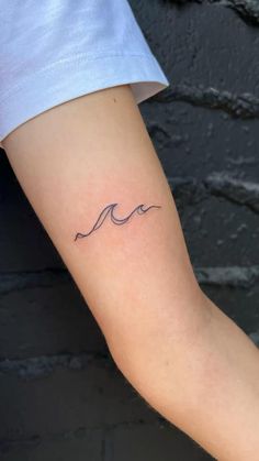 a woman's arm with a small wave tattoo on the left side of her arm