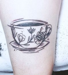 a black and white photo of a coffee cup with flowers on it's side