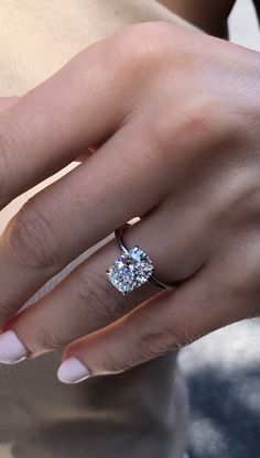 a woman's hand with a diamond ring on her finger and the other hand holding an engagement ring