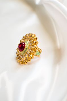 Pihu - Indian Modern Jewelry w/ Clear Kundan & Red Ruby Gemstone Stunning fine jewelry Kundan finger ring, made with hammered gold plated metal. Indian women's ring with red ruby stone sits at the centre, making this modern ring jewelry one of a kind. Beautiful design Kundans adorns this piece, adding grace. A stunning Meenakari outline enhances this piece making it perfect to be paired with any of your ethnic wear. Stone Setting: Kundan & Ruby Finish: Gold Plated Composition: Metal Alloy DELIVE Gold Jeweled Ring Jewelry, Gold Jeweled Ring, Gold Ruby Ring With 17 Jewels For Wedding, Festive Red Gold-plated Jewelry, Jeweled Open Ring Jewelry Gift, Gold Jeweled Open Ring Jewelry, Traditional Oval Ring With 17 Jewels, Gold Enamel Wedding Ring With 17 Jewels, Gold Wedding Enamel Ring With 17 Jewels