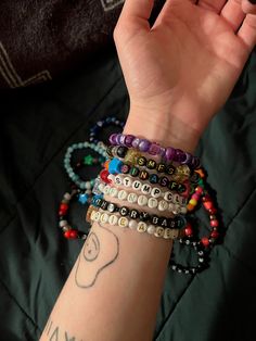 a woman's arm with several bracelets on it, including beads and charms