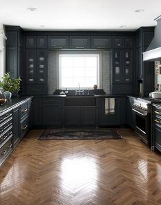 a large kitchen with black cabinets and wood flooring is seen in this image from the front view