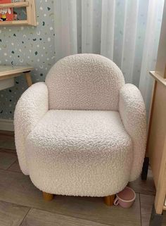 a white chair sitting on top of a wooden floor next to a wallpapered wall