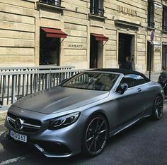 a silver car parked in front of a building next to another car on the street