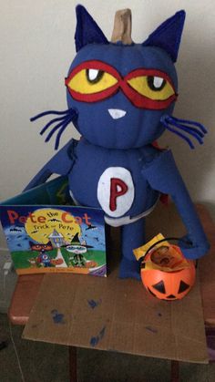 a blue cat stuffed animal sitting on top of a wooden table next to a book