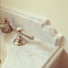 a white marble sink with chrome faucet and matching soap dispenser