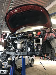 a car is being worked on in a garage with its hood up and the engine exposed