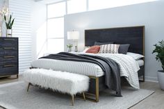 a bedroom with a bed, nightstands and plants in the corner on carpeted flooring