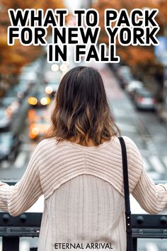 a woman standing on a bridge looking at the street with cars coming down it's sides