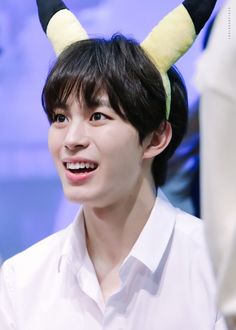 a young man with horns on his head smiles at the camera while wearing a white shirt