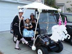 two adults and one child are posing in a golf cart decorated with paper cutouts