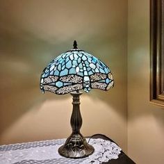 a lamp that is on top of a table next to a painting and a mirror