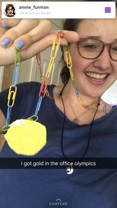 a woman wearing glasses and holding up some paper clips to her face with the caption, i got gold in the office olympics