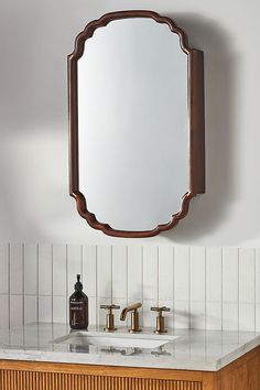 a bathroom vanity with a mirror above it and a soap dispenser on the counter