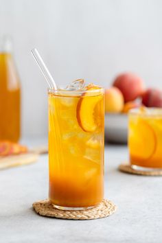 iced peach green tea lemonade in a glass with strawberries and oranges behind it