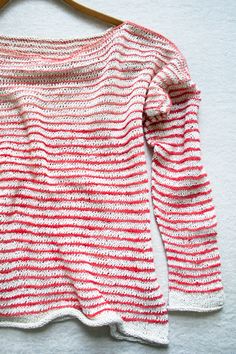 a red and white striped sweater hanging on a wooden hanger next to a pair of scissors