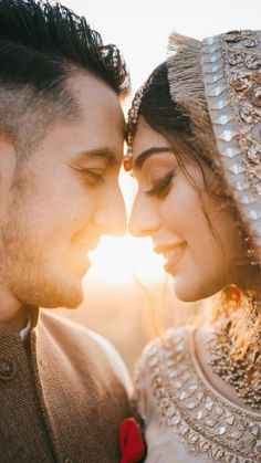 a man and woman standing next to each other in front of the sun with their faces close together