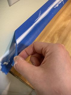 a person is peeling the edge of a piece of blue tape