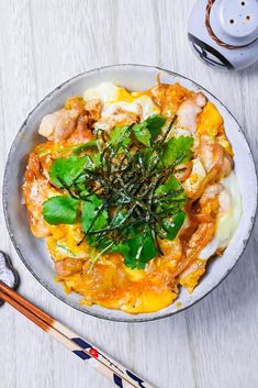 a white bowl filled with food next to chopsticks and a cup of coffee