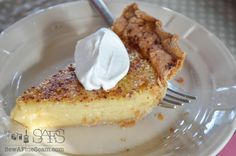 a piece of pie on a white plate with a fork and whipped cream in it