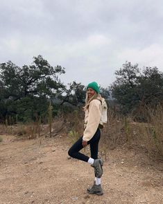 a woman standing on top of a dirt field